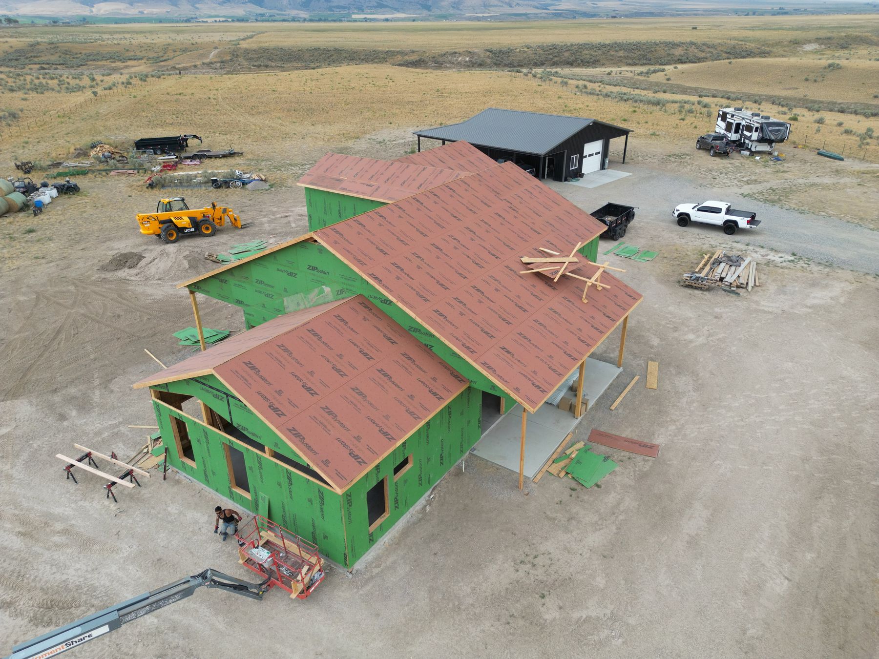 Example aerial view of a shop-house combination barndominium under construction next to an existing steel shop building