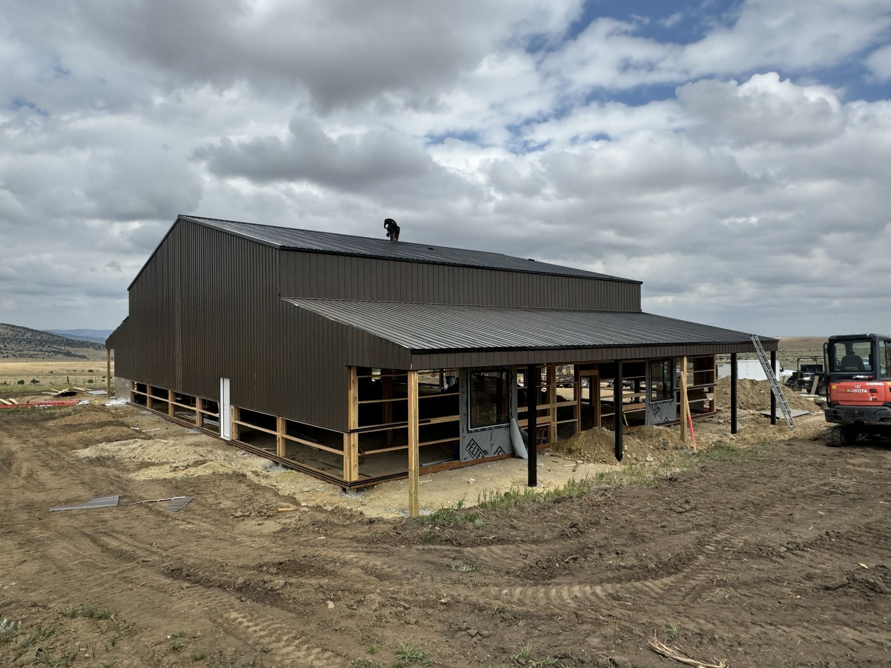 Example barndominium under construction with metal siding and covered wraparound porch, illustrating typical construction style